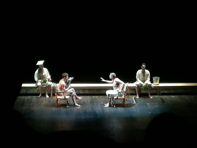 Four people seated on a dimly lit stage during a performance