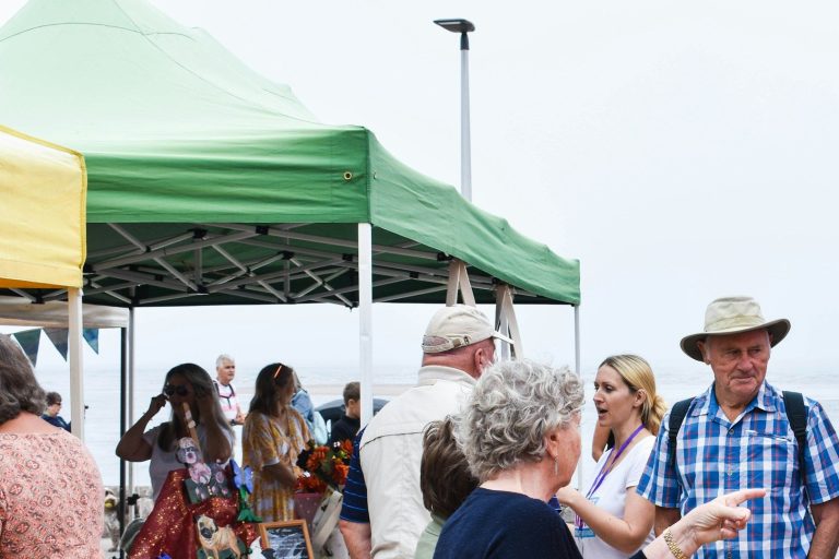 Community members talking at an outdoor market with tents