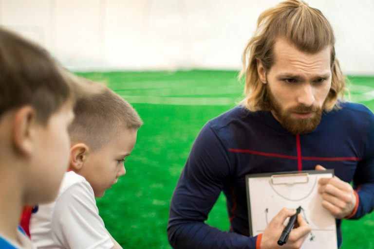 Coach with a clipboard talking with young players on a field