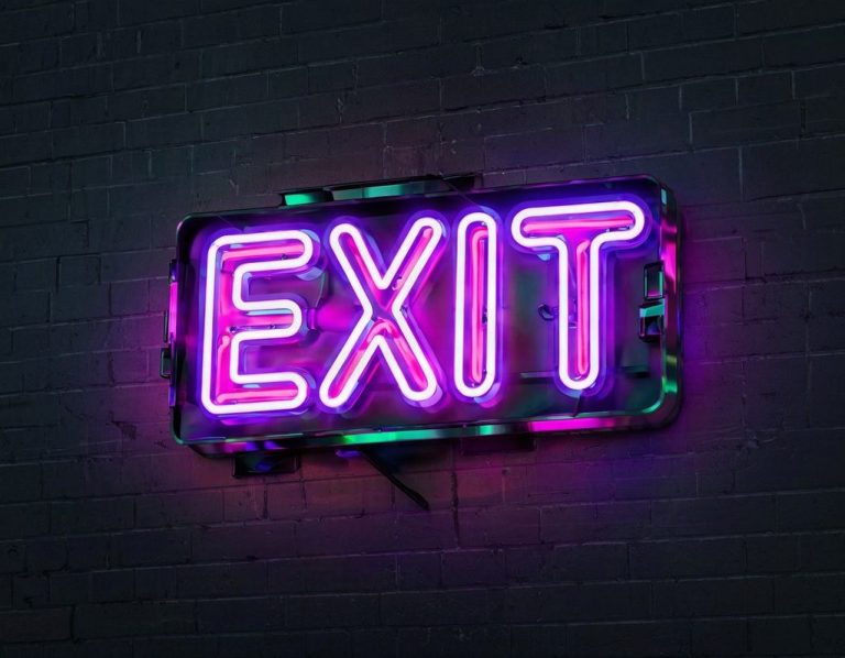 Neon EXIT sign on a dark brick wall